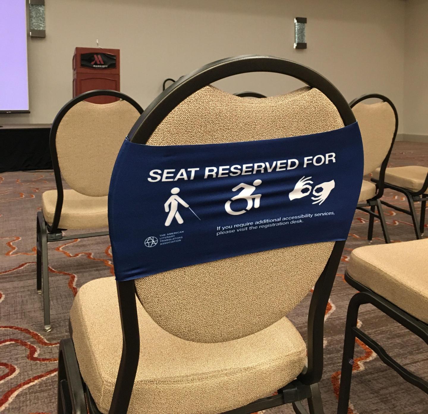 Image of a stretchy blue seat band with disability access symbols marking seating for those who need to be close to the front.